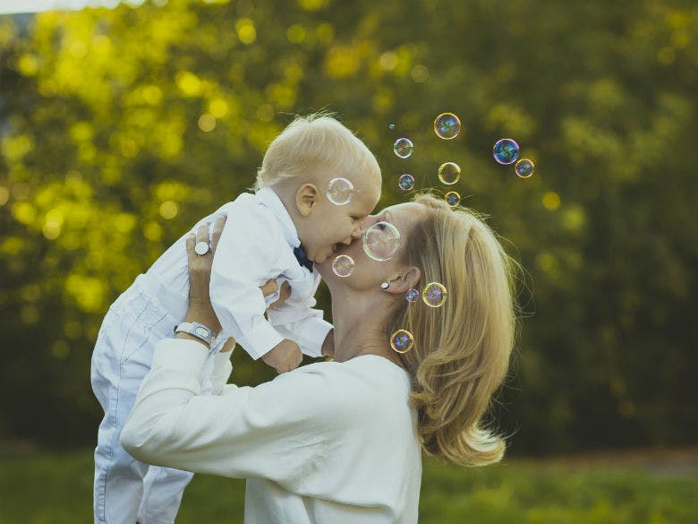happy-son-with-mother-in-garden-and-soap-bubbles