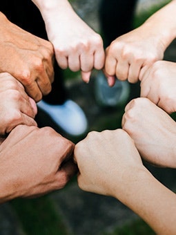 Mãos de diferentes pessoas em punho a formar um círculo.