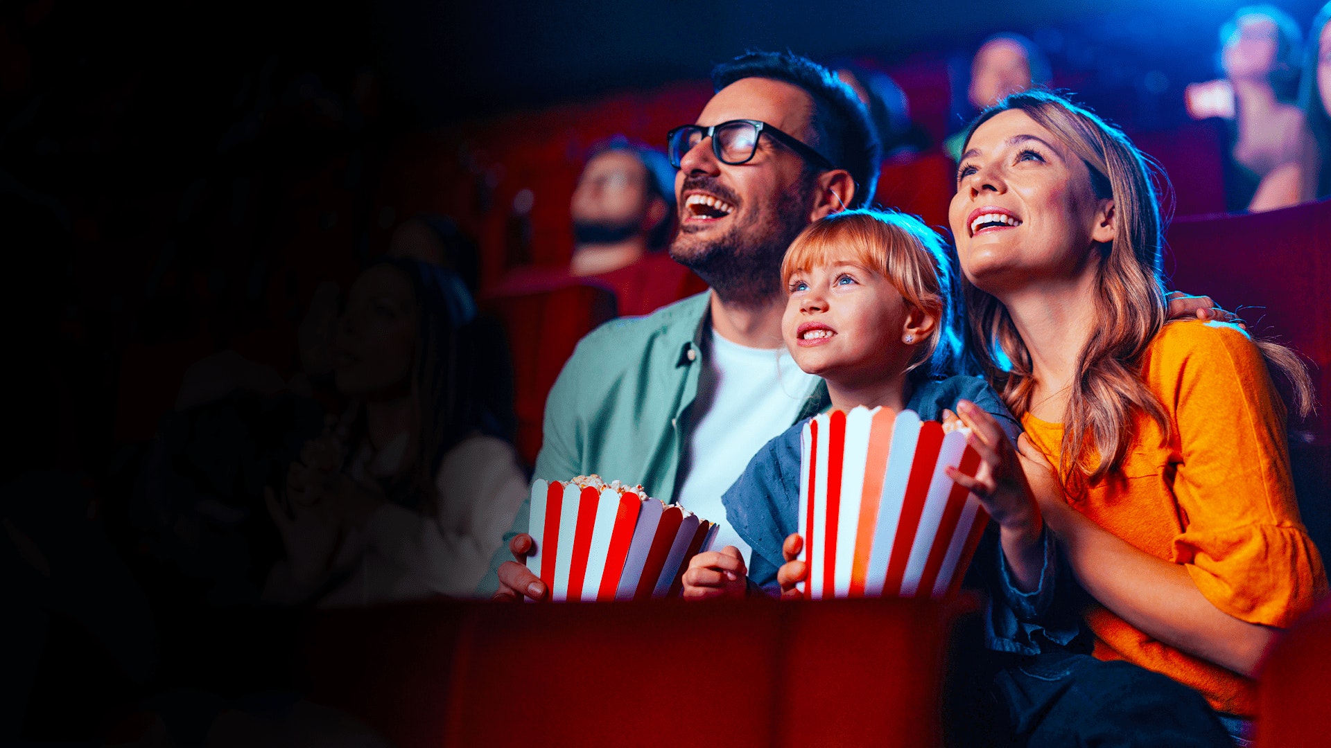 família sorridente no cinema a comer pipocas